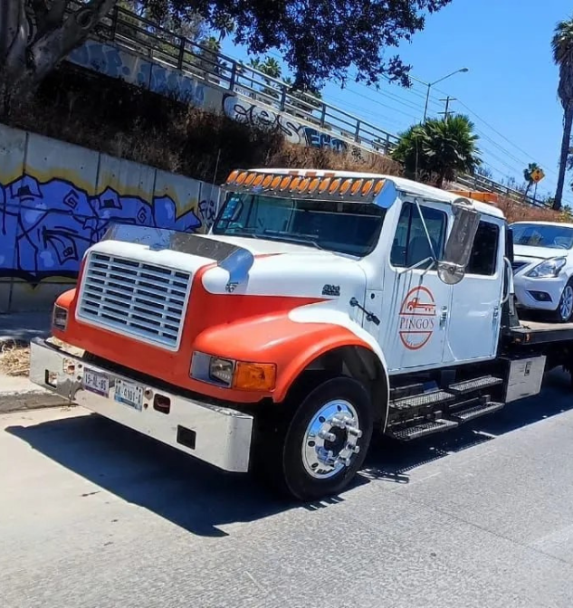 Grúa de plataforma trasladando un automóvil en Tijuana, servicio de auxilio vial