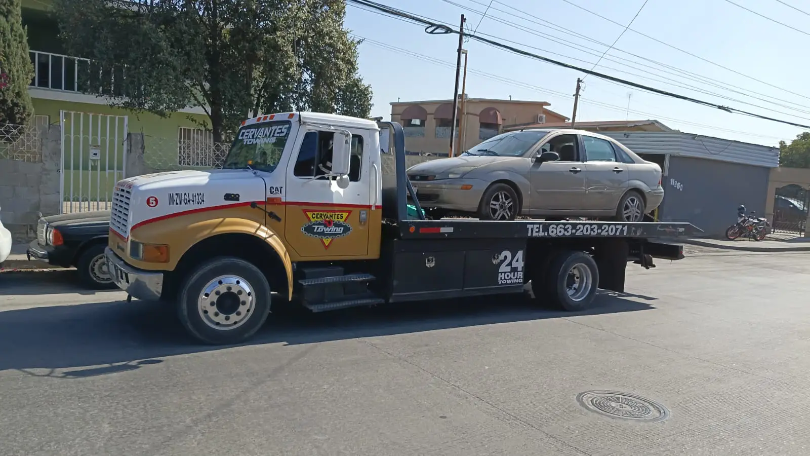 Grúa de plataforma trasladando un automóvil en Tijuana, servicio de auxilio vial